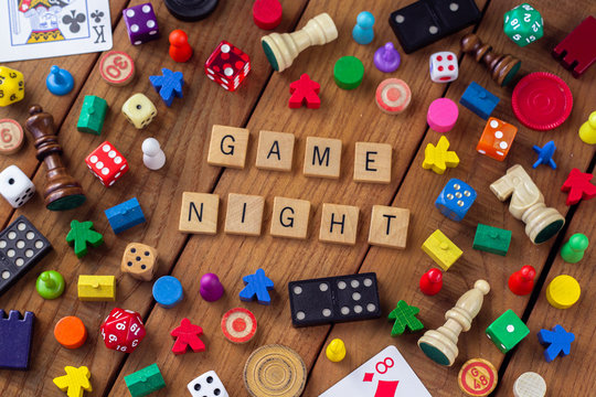 image of tiles spelling "game night" surrounded by dice, meeple, chess pieces, and other game pieces