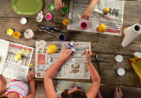 Image of children painting fruit on top of newspapers.