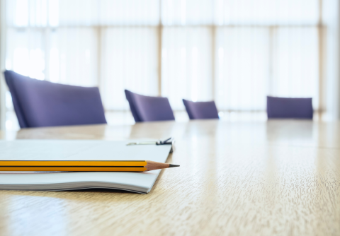 Image of table with four chairs and notebook with pencil.